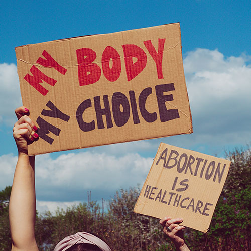 Person holding protest signs reading my body, my choice.