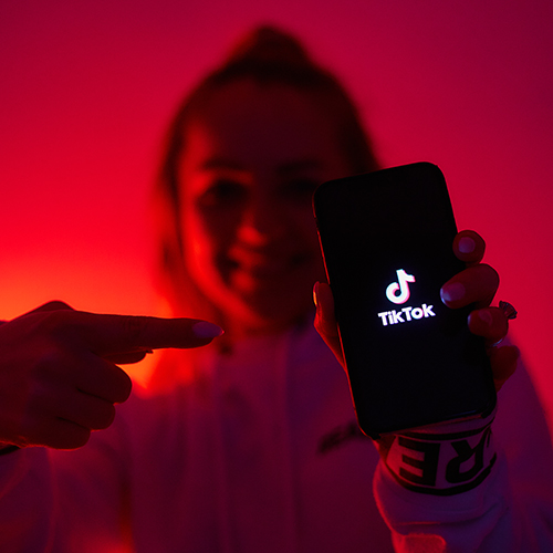 Young person holding phone displaying TikTok logo.