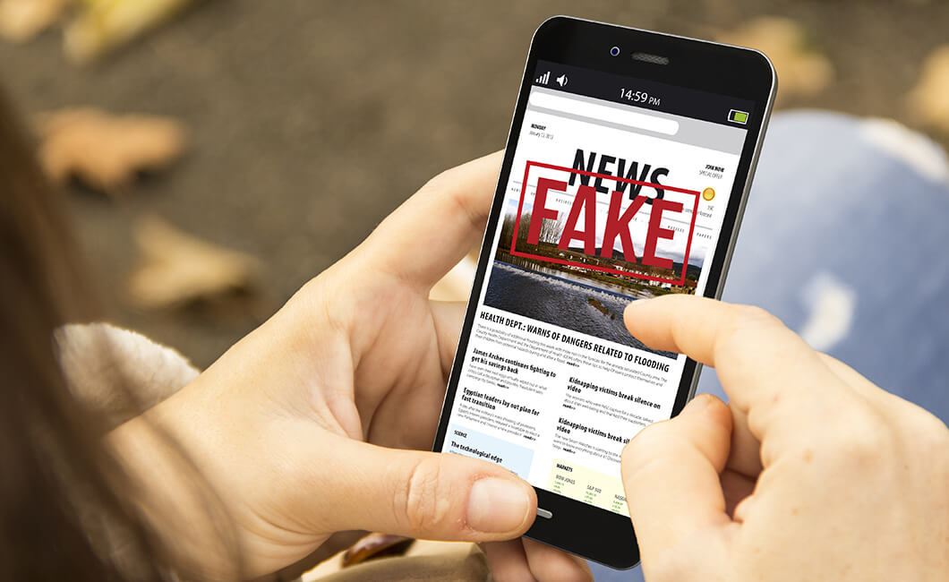 A person holding a phone displaying fake news.