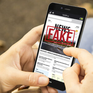 A person holding a phone displaying fake news.