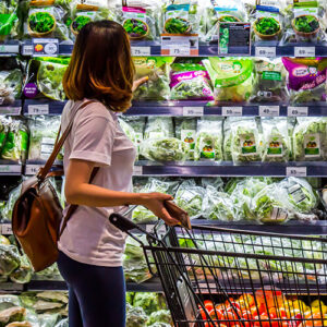 Woman shopping for lettuce in a grocery story.