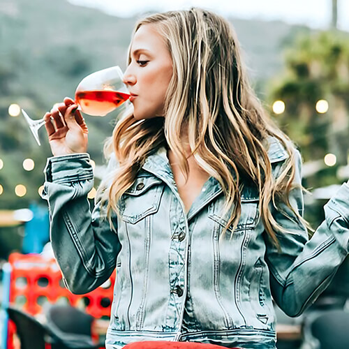A woman drinking wine outdoors.
