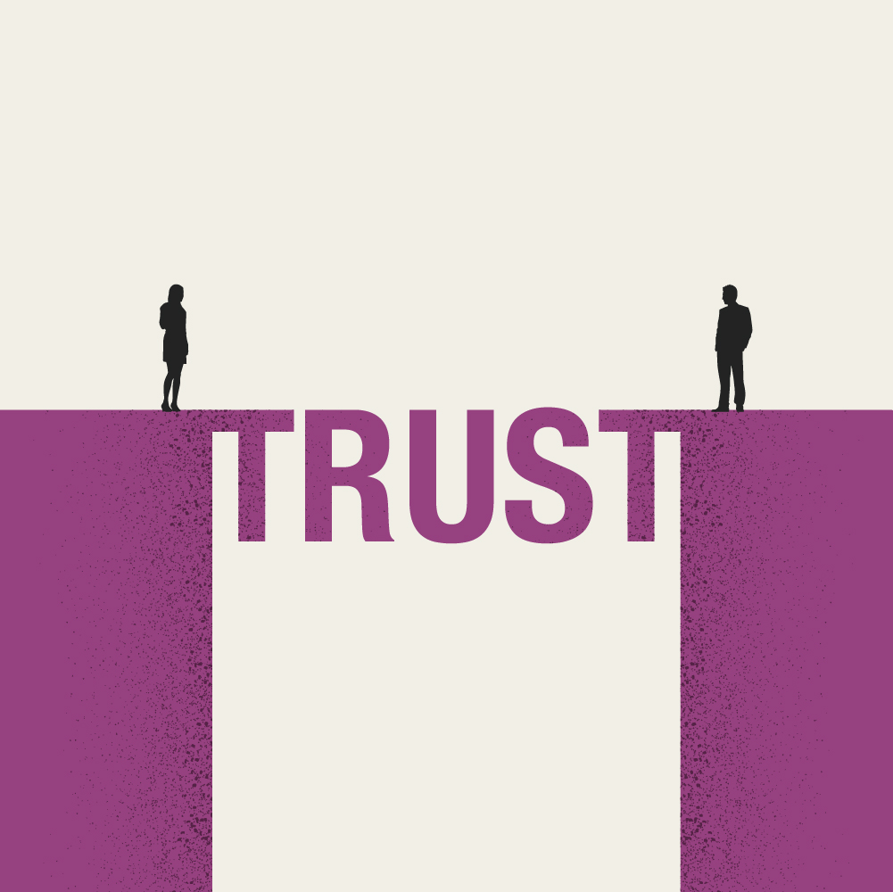 Two people stand facing each other on opposite sides of a bridge that spells trust