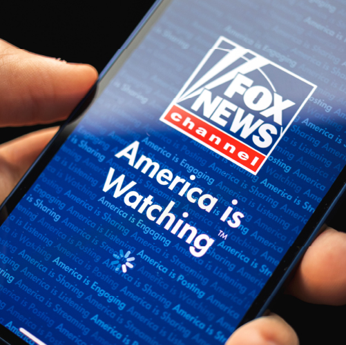Person holding phone with Fox News app loading