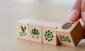 Wooden blocks symbolizing the 3 pillars of ESG, with someone pulling the 4th block that says "ESG" away