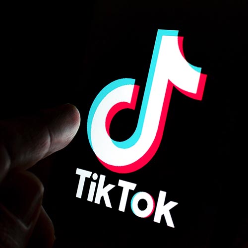 Finger on a phone screen with the TikTok app on it