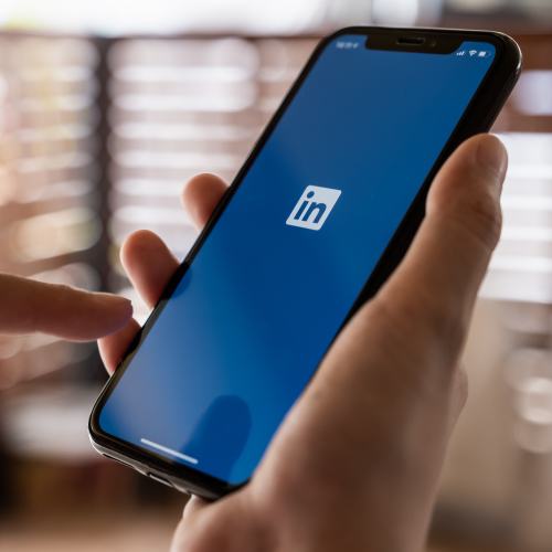 Hand holding phone showing the LinkedIn logo.